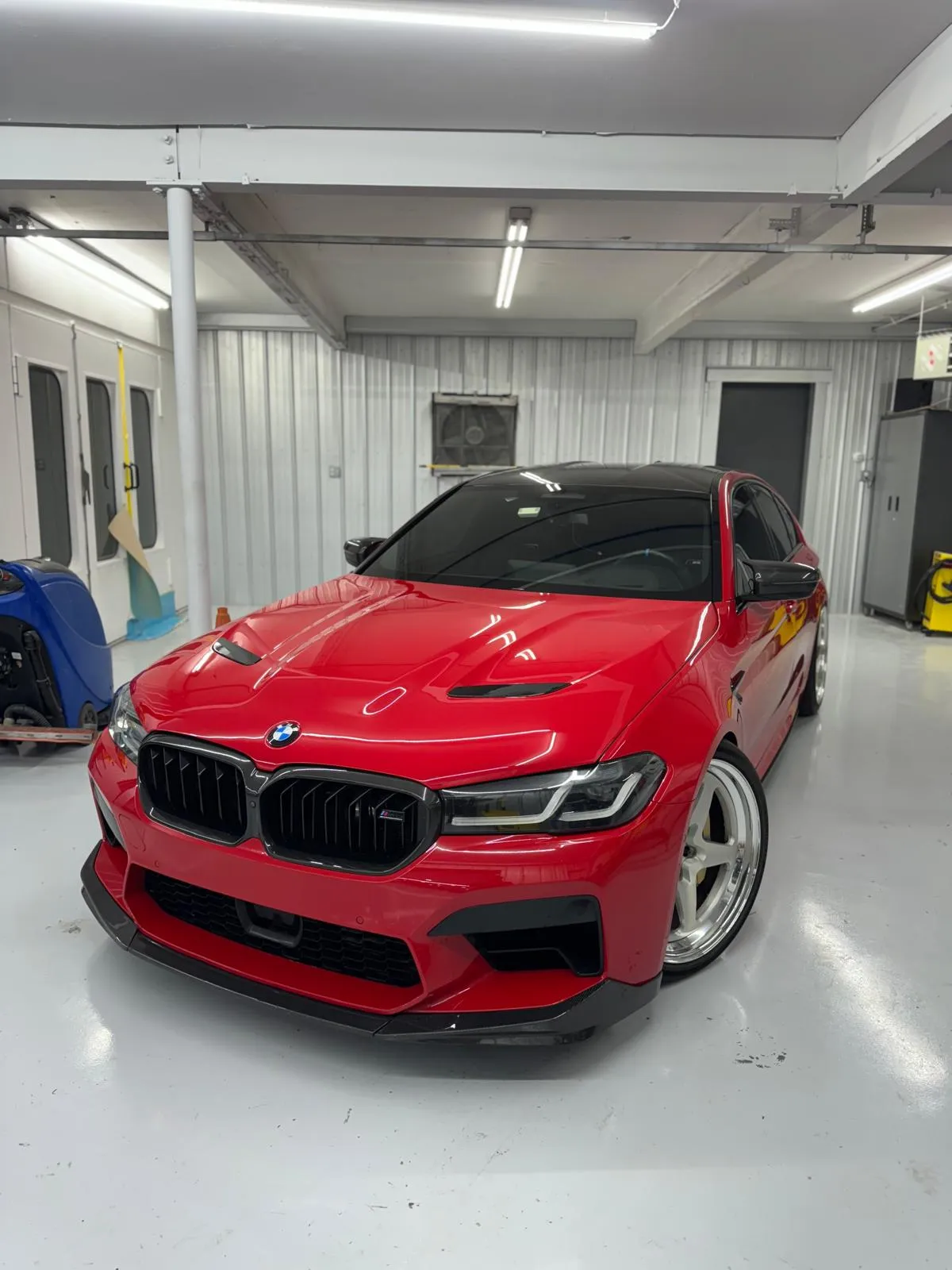 Red F90 M5 with an M5 CS hood, carbon front lip, and custom white wheels. Every panel was color matched for a clean OEM-plus finish.