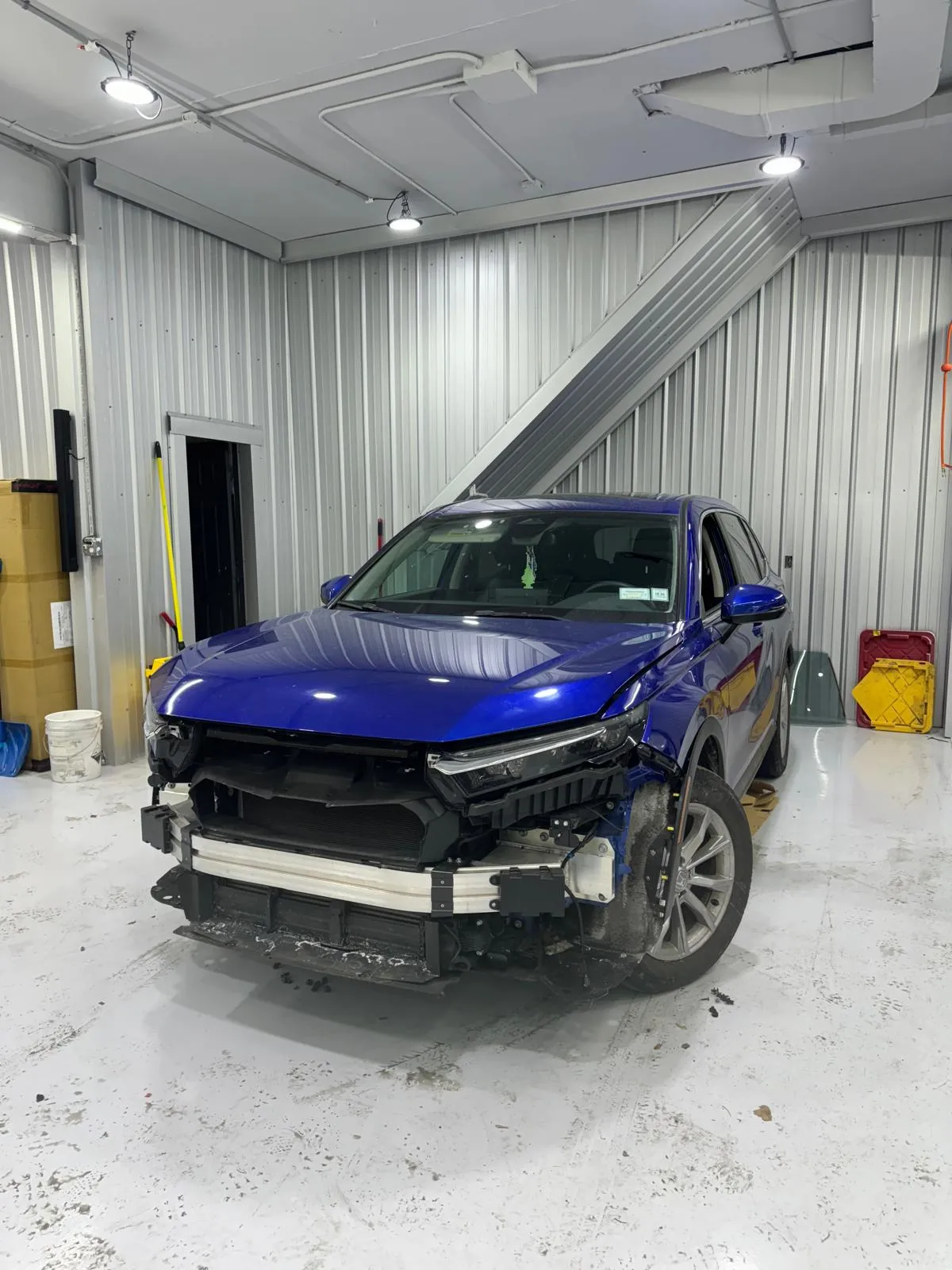 Blue SUV with front bumper removed for collision repair at PMW Auto Body